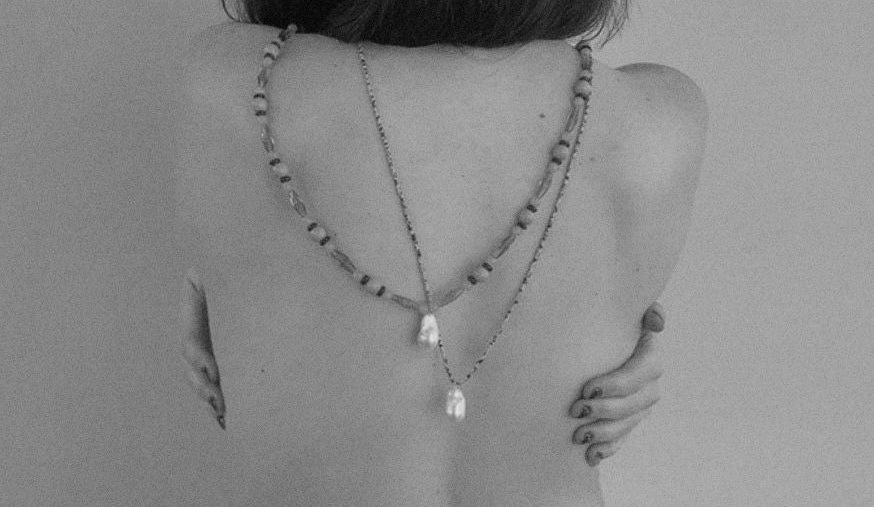 Person wearing a necklace with a plain background